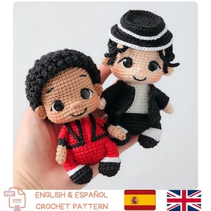 Peut inclure: Deux petites poupées au crochet avec des cheveux foncés et des yeux noirs. L'une porte une veste rouge avec des bordures noires et des détails blancs. L'autre porte une veste noire, une chemise blanche, un pantalon noir, des chaussettes blanches et un chapeau noir avec une bande blanche.