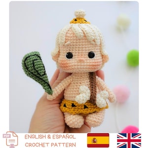 May include: A crocheted caveman doll with a cream-coloured body, blonde hair, and a yellow and brown skirt. The doll holds a green club. The text "ENGLISH & ESPAÑOL CROCHET PATTERN" is visible.