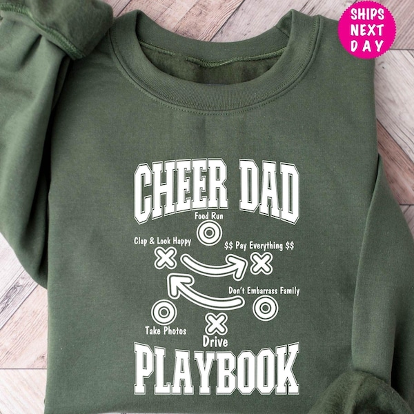 May include: Green sweatshirt with a white graphic that says "Cheer Dad Playbook" and includes a diagram with instructions like "Clap & Look Happy", "Food Run", "$$ Pay Everything $$", "Don't Embarrass Family", and "Take Photos".