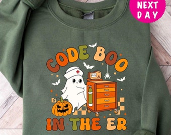 Könnte beinhalten: Dunkelgrünes Sweatshirt mit einem Halloween-Motiv. Das Design zeigt einen Geist mit Krankenschwestermütze, einen Kürbis, Fledermäuse und den Text "CODE BOO IN THE ER" in orangefarbenen und braunen Buchstaben.