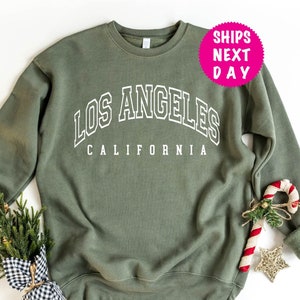 May include: A green sweatshirt with white text that reads "Los Angeles California".