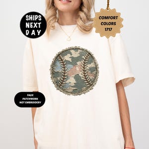 Puede incluir: Camiseta color marfil con un diseño de béisbol con un patrón de camuflaje en verde, marrón y azul. La camiseta tiene el texto "Comfort Colors 1717", "Ships Next Day", "Faux Patchwork Not Embroidery" e "Ivory".