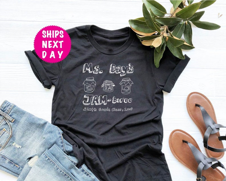 May include: Black t-shirt with white text that reads "Ms. Day's JAM-boree Sixth Grade Class, 2023". The text is surrounded by three drawings of jars with lids.