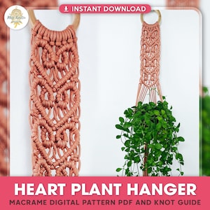 以下が含まれることがあります： 木製のリングが付いた、桃色のコードで作ったマクラメのハート型のプラントハンガー。ハンガーは緑の葉の入った鉢植えの植物を吊り下げています。画像には「HEART PLANT HANGER」と「MACRAME DIGITAL PATTERN PDF AND KNOT GUIDE」のテキストが含まれています。