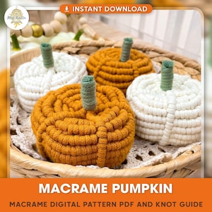 May include: Three macrame pumpkins, one white and two orange, are displayed in a wicker basket. The pumpkins are made with rope and have a green stem. The image includes the text "Macrame Pumpkin" and "Macrame Digital Pattern PDF and Knot Guide".