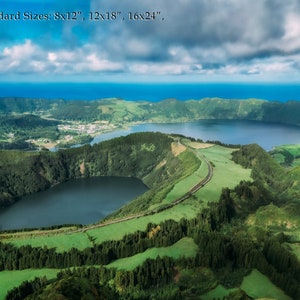 May include: Aerial view of a lush green landscape with two lakes. The larger lake is surrounded by hills and the smaller lake is nestled in a valley. The sky is blue with white clouds.