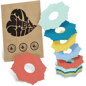 Può includere: Una pila di cerchi di tessuto colorati con bordi smerlati e un foro centrale, in tonalità di blu, giallo e rosso. Un sacchetto di carta marrone con la scritta "My Sweet Stitch" e tre sigilli circolari sullo sfondo.