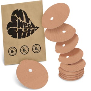 Könnte beinhalten: Eine braune Papiertüte mit dem Text "Sweet Stitch" in Herzform und mehrere beige, oval geformte medizinische Pflaster mit einem zentralen Loch. Die Tüte hat drei runde Siegel mit Text. Die Pflaster sind gestapelt und verstreut.