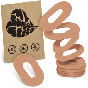 May include: A collection of tan oval medical patches with a central aperture, alongside a brown paper packet. The packet displays a black heart-shaped logo with the text "Sweet Stitch" and three circular seals.