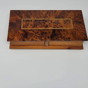 May include: A wooden box with a burl wood top and a gold inlay. The box has two drawers.