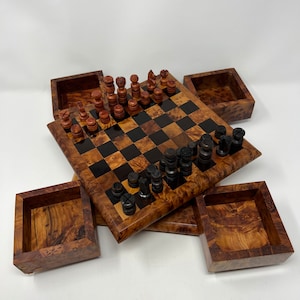 May include: A wooden chess set with black and brown pieces, stored in a wooden box with four compartments. The chessboard is made of dark and light wood squares.