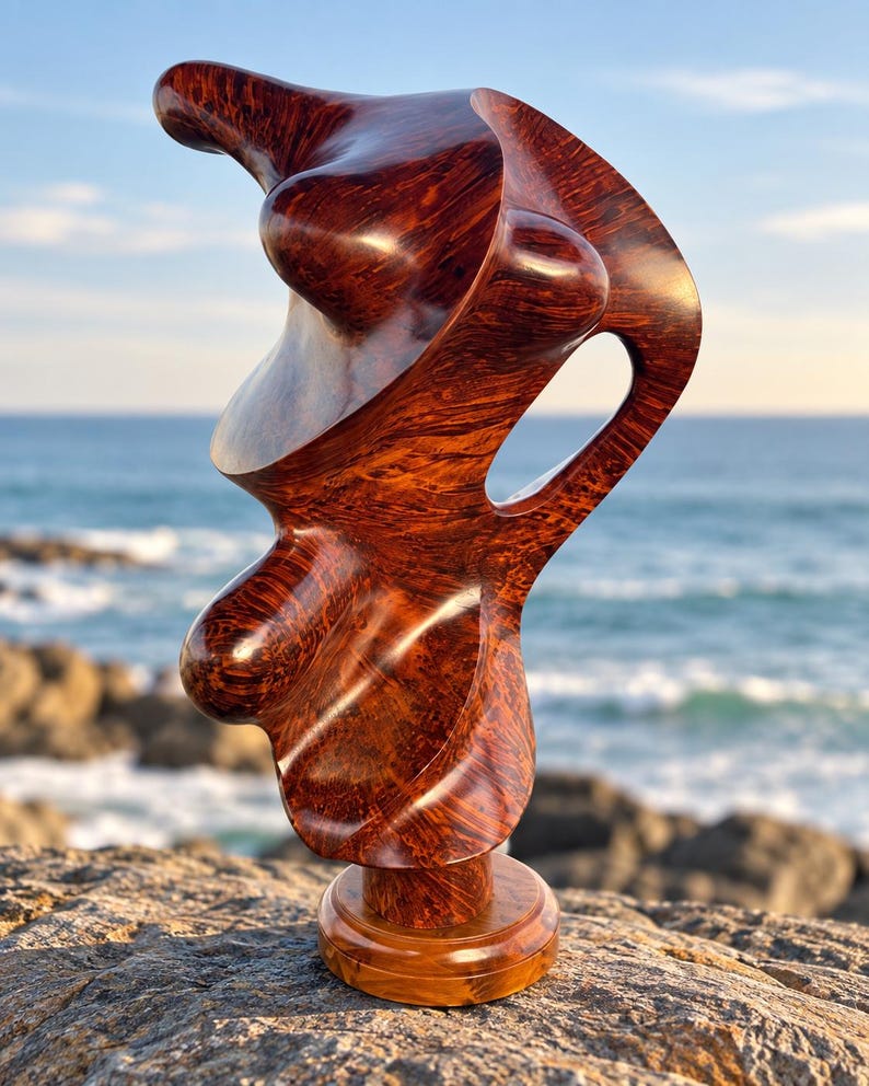 May include: A polished, dark reddish-brown wooden sculpture with a complex, organic, and fluid shape. The piece features a smooth, glossy finish that highlights the intricate grain patterns of the wood, resting on a circular wooden base.