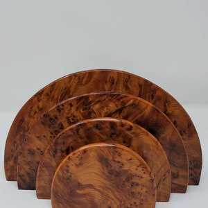 May include: A set of four wooden half-circle trays, nested together. The trays are made of a light brown wood with a unique grain pattern.