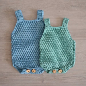 May include: Two crocheted baby onesies, one blue and one green, with wooden buttons.