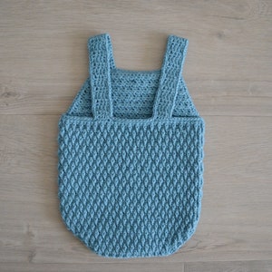 May include: A light blue crocheted baby romper with straps. The romper has a textured diamond pattern.