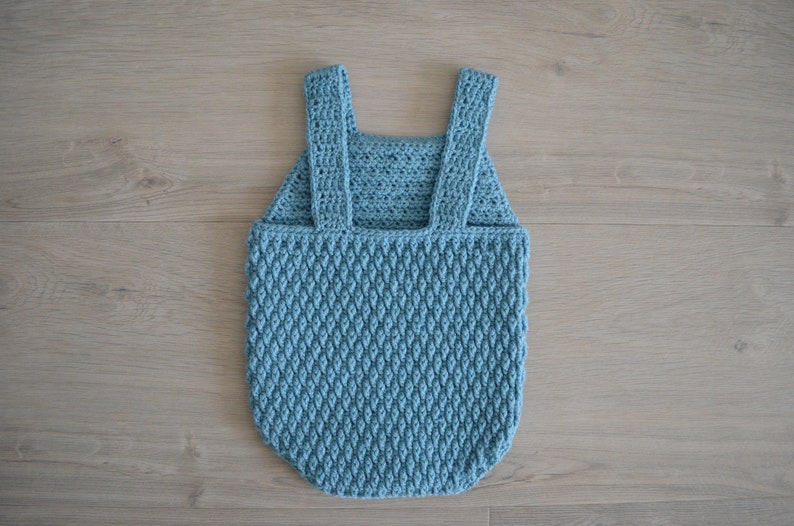 May include: A light blue crocheted baby romper with straps. The romper has a textured diamond pattern.