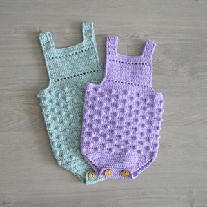 May include: Two crocheted baby onesies, one in light green and one in lavender, with a textured, bumpy design. Both onesies have wooden buttons.