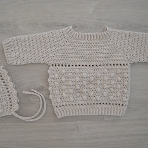 Peut inclure: Un pull et un bonnet assortis en crochet beige avec un motif texturé en points bouclés.