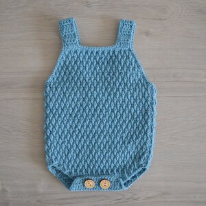May include: A light blue crocheted baby onesie with wooden buttons.