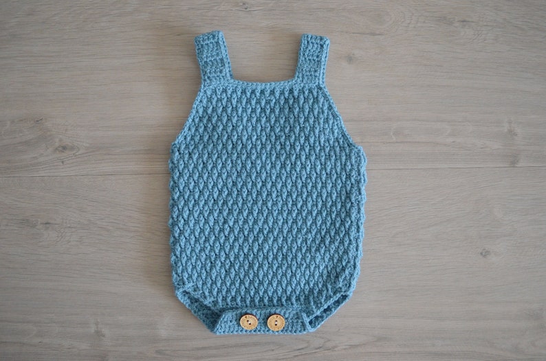 May include: A light blue crocheted baby onesie with wooden buttons.