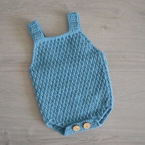 May include: A light blue crocheted baby onesie with wooden buttons.