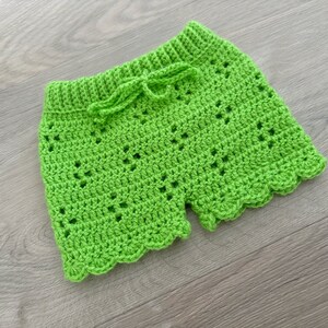 Op de afbeelding: Limoengroene gehaakte shorts met een gegolfde zoom en een strik aan de taille.