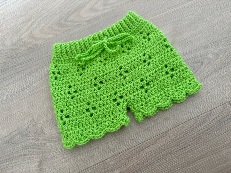 Op de afbeelding: Limoengroene gehaakte shorts met een gegolfde zoom en een strik aan de taille.