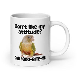 May include: White ceramic mug with the text "Don't like my attitude?" and "Call 1800-BITE-ME." A colorful parrot is pictured below the text. The mug has a white handle.