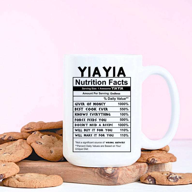 May include: A white ceramic mug featuring black text that reads YIA YIA Nutrition Facts, listing attributes like Giver of Money 1000%, Best Cook Ever 550%, Knows Everything 100%, Force Feeds You 500%, Doesn't Need a Recipe 1000%, Will Buy It For You 110%.