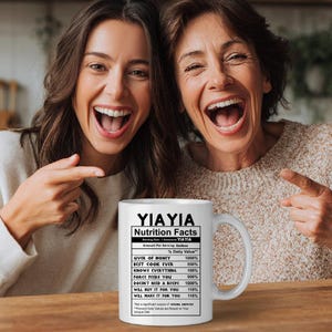 May include: A white ceramic mug featuring black text that reads YIAYIA Nutrition Facts, listing humorous attributes like Giver of Money 1000%, Best Cook Ever 550%, Knows Everything 100%, Force Feeds You 500%, and Will Make It For You 110%.