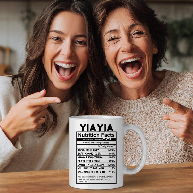 May include: A white ceramic mug featuring black text that reads YIAYIA Nutrition Facts, listing humorous attributes like Giver of Money 1000%, Best Cook Ever 550%, Knows Everything 100%, Force Feeds You 500%, and Will Make It For You 110%.