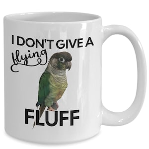 May include: White ceramic coffee mug featuring a green and brown parakeet illustration and the text "I don't give a flying fluff".