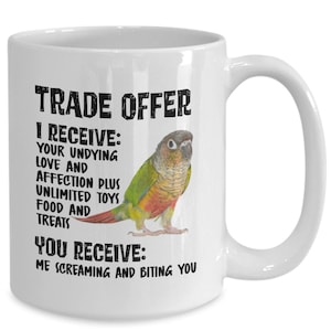 May include: White ceramic coffee mug featuring a green and brown parrot illustration. The mug has black text that reads "TRADE OFFER I RECEIVE: YOUR UNDYING LOVE AND AFFECTION PLUS UNLIMITED TOYS FOOD AND TREATS YOU RECEIVE: ME SCREAMING AND BITING YOU"