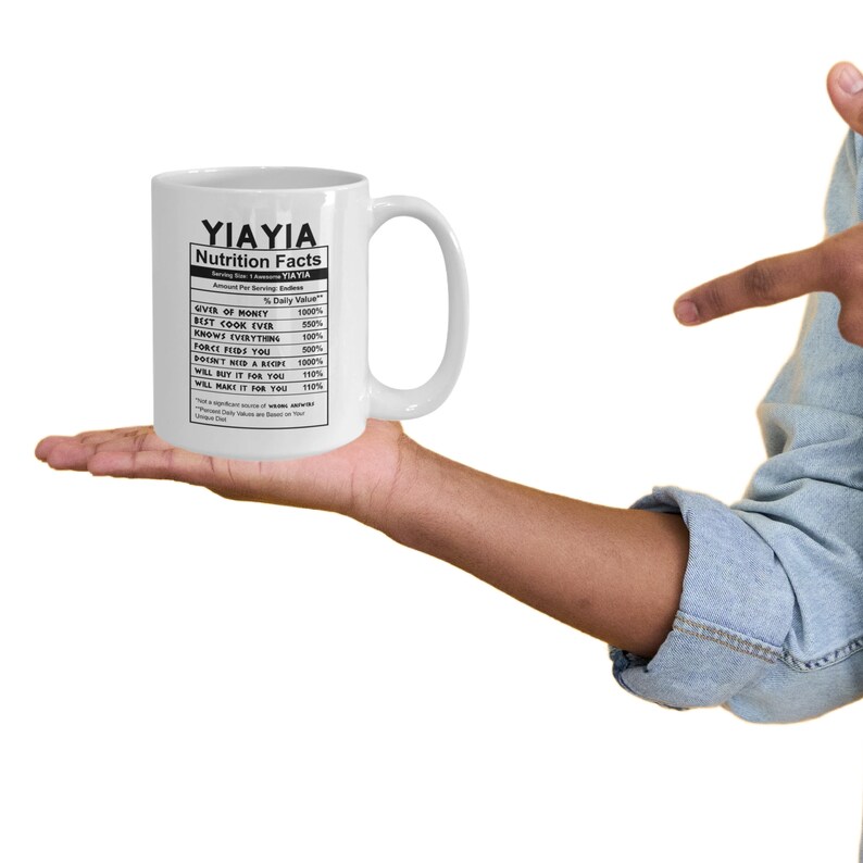 May include: A white ceramic mug featuring black text printed in a nutrition facts label style. The text reads YIAYIA Nutrition Facts, listing attributes like Giver of Money 1000%, Best Cook Ever 550%, Knows Everything 100%, and Force Feeds You 500%.