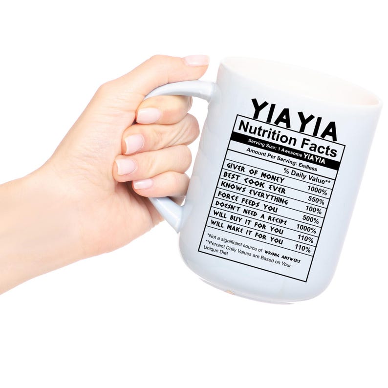 May include: A white ceramic mug featuring a black printed nutrition facts label that reads YIAYIA Nutrition Facts, listing attributes like Giver of Money, Best Cook Ever, Knows Everything, Force Feeds You, and other humorous daily values.