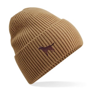 Könnte beinhalten: Eine braune Strickmütze mit einer gestickten Silhouette eines braunen Hundes auf der Vorderseite.