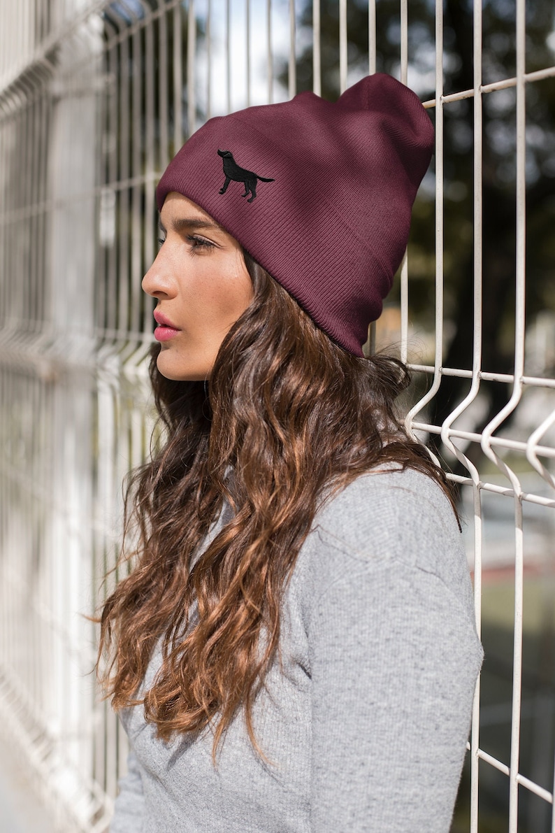 May include: A maroon beanie with a black silhouette of a dog embroidered on the front.
