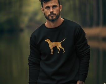 May include: A man wearing a black sweatshirt with a gold silhouette of a dog on the front. He is standing in a forest and has his hands in his pockets. He is wearing brown cargo pants.