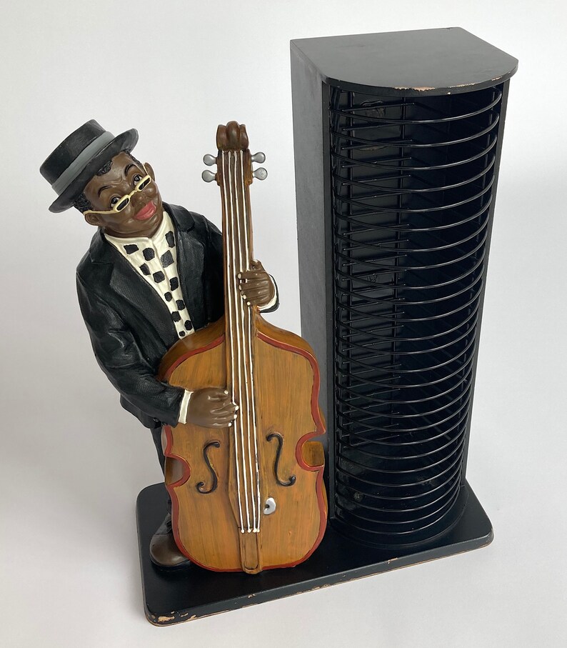 Pu&ograve; includere: Una torre per CD nera con una statuetta di un uomo che suona il basso. La statuetta &egrave; in resina dipinta ed &egrave; in posizione eretta. La torre ha una struttura in metallo nero e pu&ograve; contenere fino a 72 CD.