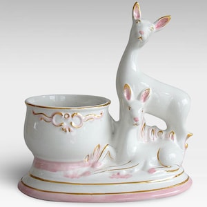 May include: White ceramic planter with a pink and gold trim, shaped like a deer with a fawn nestled beside it.