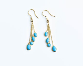May include: A pair of gold dangle earrings with turquoise stones. The earrings have multiple strands of chain with a small clear stone at the top.