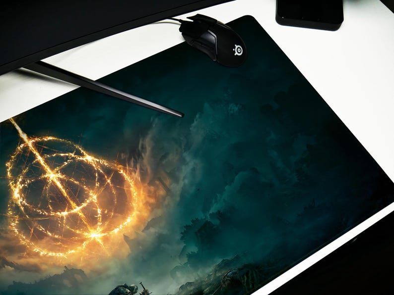 K&ouml;nnte beinhalten: Ein gro&szlig;es rechteckiges Gaming-Mauspad mit detailliertem Fantasy-Landschaftsdesign. Das Pad hat einen dunkel t&uuml;rkisblauen und blauen Hintergrund mit einem hellgoldenen, kreisf&ouml;rmigen Design in der Mitte. Eine schwarze Maus und ein schwarzer Computermonitor sind sichtbar.