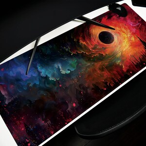 May include: A rectangular mouse pad featuring a vibrant cosmic design. The artwork depicts a swirling nebula with a black hole at the center, surrounded by fiery oranges, reds, and blues. The pad is designed for a computer setup.