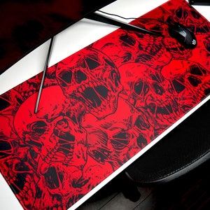 May include: Red gaming mouse pad with a skull design. The mouse pad is covered in black and white skulls on a red background.
