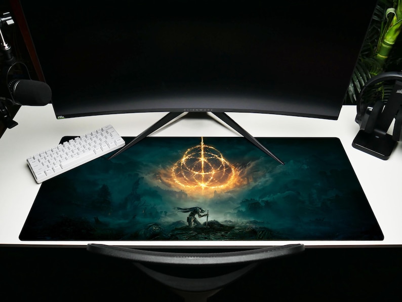 K&ouml;nnte beinhalten: Ein gro&szlig;es rechteckiges Gaming-Mauspad mit einer Fantasy-Landschaft mit einem leuchtenden goldenen Symbol und einer Silhouette. Das Pad ist &uuml;berwiegend t&uuml;rkis und schwarz, mit einer wei&szlig;en Tastatur und einem schwarzen Monitor im Hintergrund.