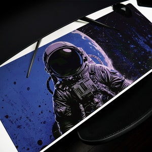 May include: A blue and black space-themed mousepad with a graphic of an astronaut floating in space. The astronaut is wearing a white spacesuit with a black helmet and is surrounded by stars and a planet.