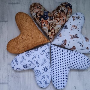 Peut inclure: Plusieurs coussins en forme de cœur. L'un est en liège, d'autres présentent des motifs de chiens et de chats, des motifs nautiques et un motif à pois bleu marine. Ces coussins décoratifs sont disposés en cercle.