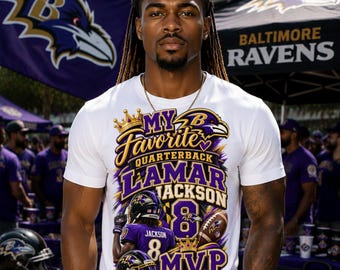 May include: A white t-shirt featuring a graphic print that says My Favorite Quarterback Lamar Jackson MVP. The design includes a football player in a purple jersey, a football, two gold crowns, and the Baltimore Ravens logo in purple and gold.