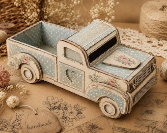 May include: A decorative wooden truck planter featuring a distressed cream and light blue polka dot finish. The truck is adorned with floral decals on the bonnet and wings, a heart-shaped cutout on the door, and a hollow bed for storage.