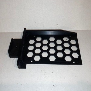 May include: Black plastic 3D printed hard drive cage with a honeycomb pattern.